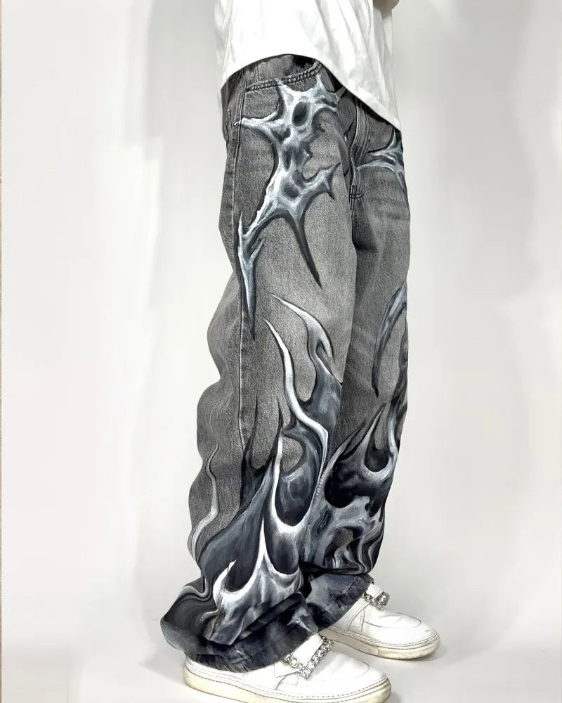 Gray jeans with flame design worn by a person on a white background