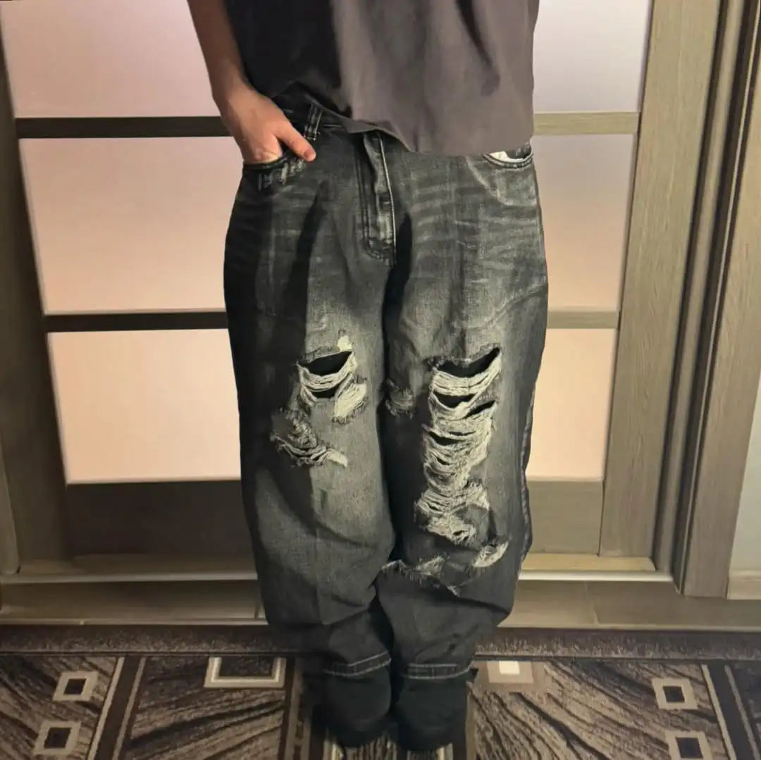 Person wearing ripped jeans standing in front of a mirror.