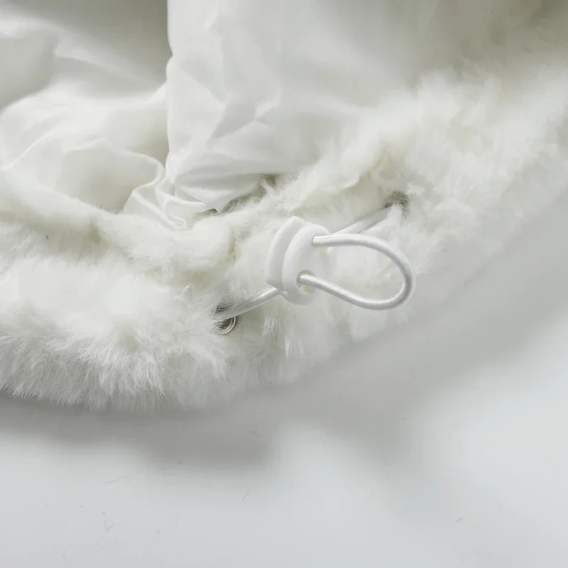 Close-up of a fluffy white blanket with a button on a light gray background