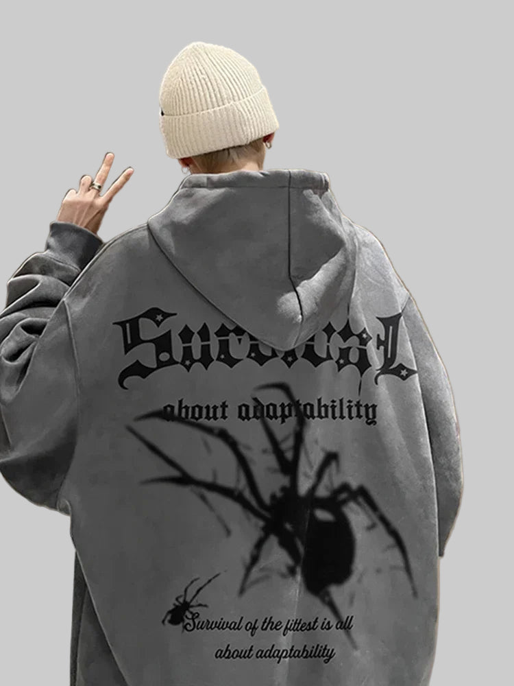 Person wearing a gray hoodie with a spider graphic and text on the back, standing indoors.
