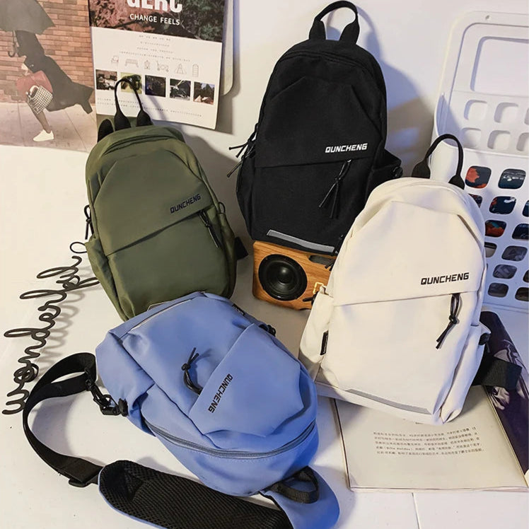 Four backpacks in green, black, blue, and white on a surface with visible text and graphics.