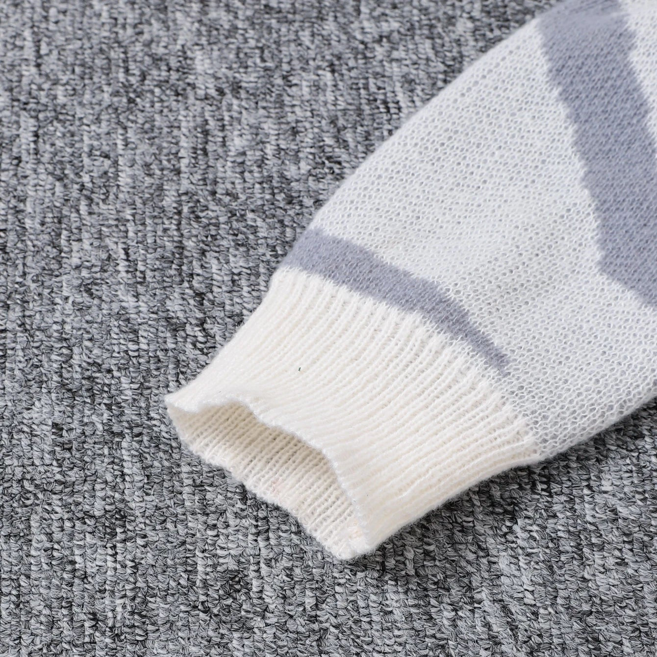 Close-up of a striped sweater sleeve on a textured gray surface