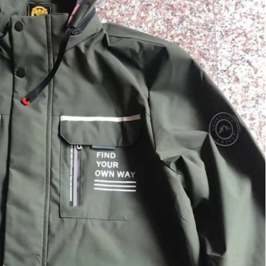 Green raincoat with a brand logo on a speckled surface
