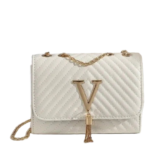 White handbag with gold chain and tassel on a white surface