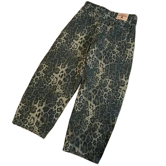 Leopard print pants on a wooden floor with white sneakers beside them.