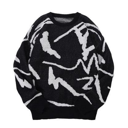 Black sweater with white abstract patterns on a gray surface with sunglasses and a cap.