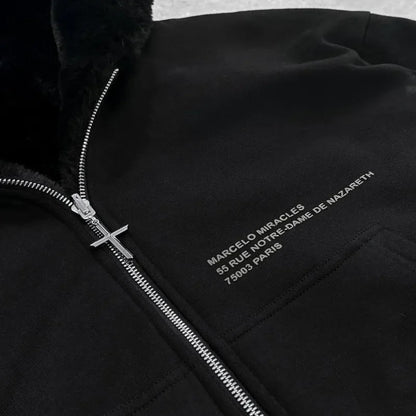 Black jacket with silver zipper and embroidered text on a textured gray background
