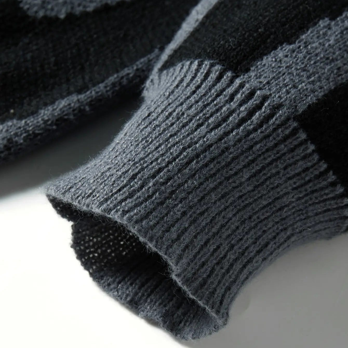 Close-up of a dark gray knitted sweater sleeve on a light background