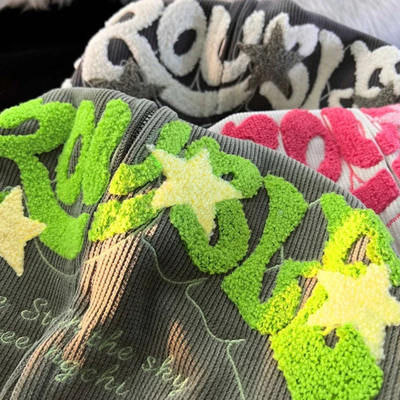 Close-up of embroidered green leaves and stars on a fabric with text.