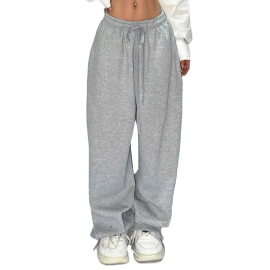 Person wearing a white cropped top and gray sweatpants on a plain background