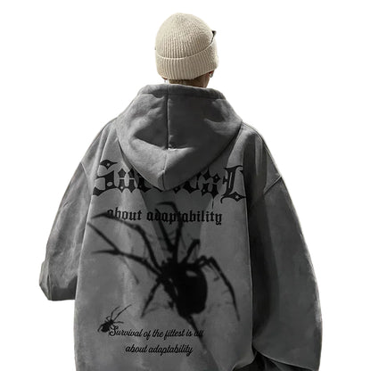 Person wearing a gray hoodie with spider design and text in a kitchen