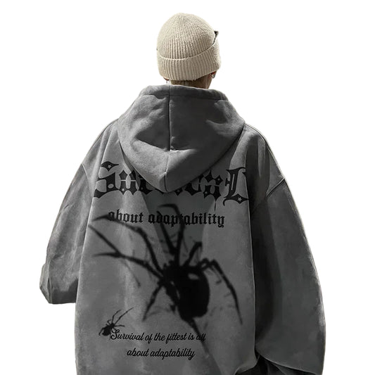 Person wearing a gray hoodie with spider design and text in a kitchen