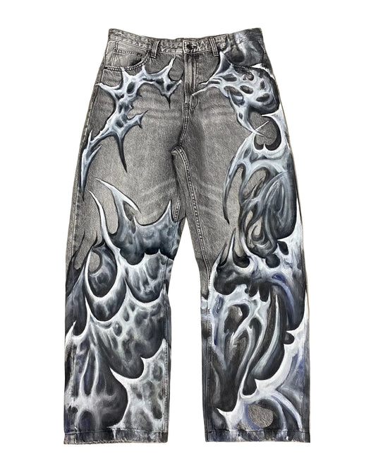 Gray jeans with black tribal designs on a textured brown background