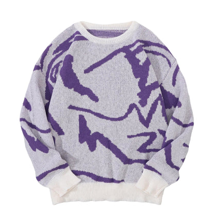 Gray sweater with purple abstract patterns on a gray surface with white shoes and a white blanket in the background.