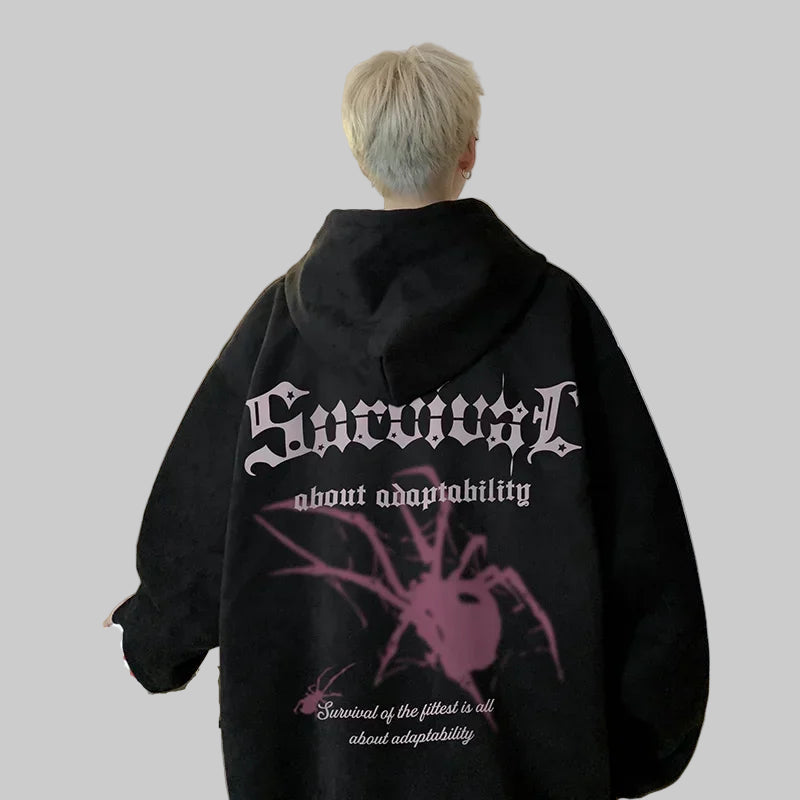 Person wearing a black hoodie with text and a spider design in a kitchen.