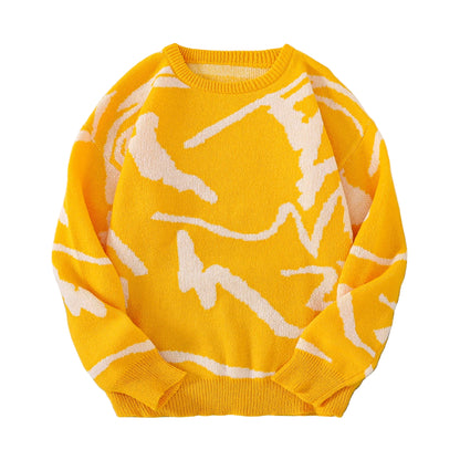 Yellow sweater with white patterns on a gray surface with sunglasses and a white box.