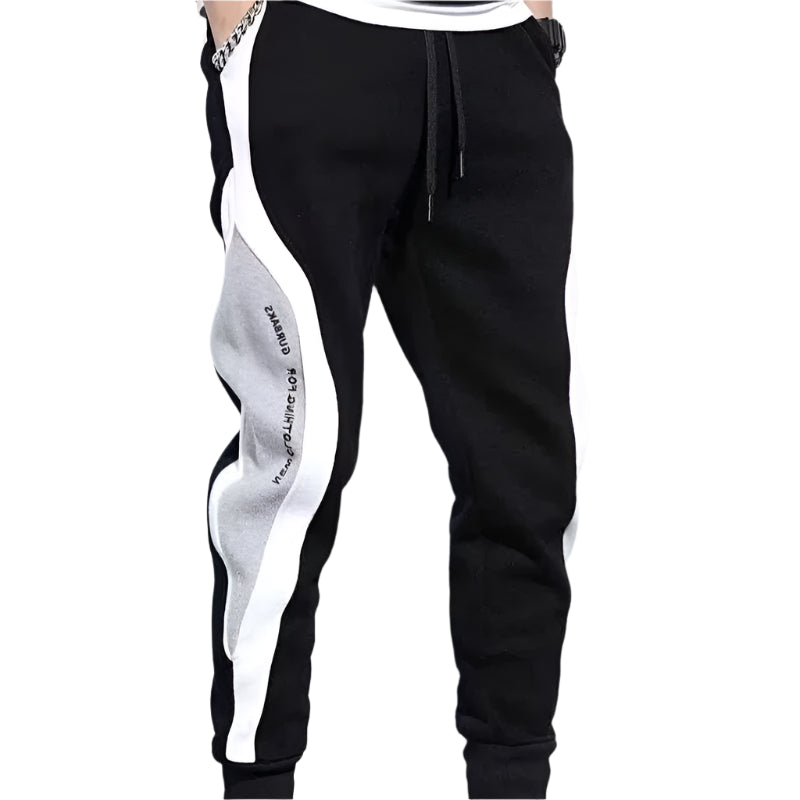 Black jogger pants with white and gray side panels on a gray background