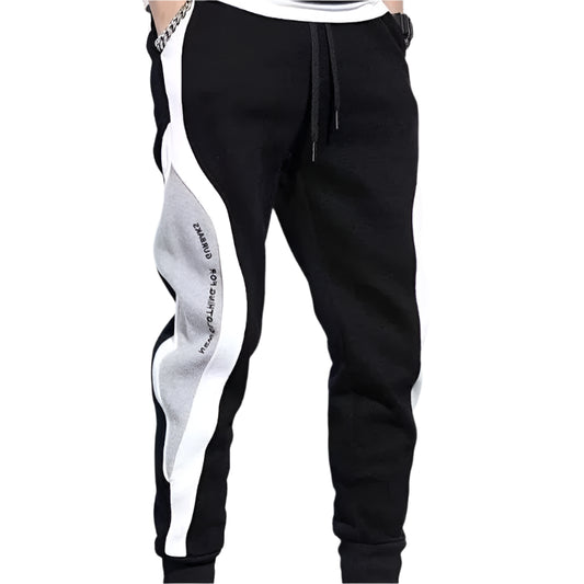 Black jogger pants with white and gray side panels on a gray background