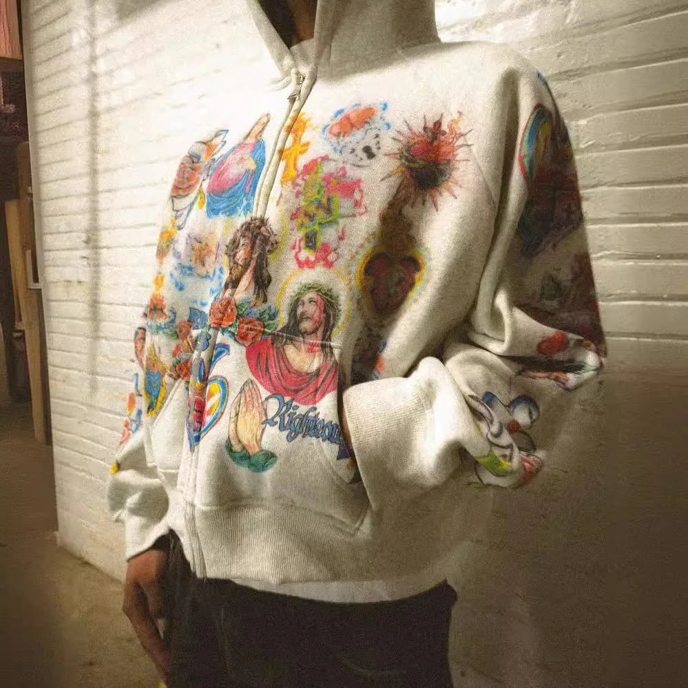 White hoodie with colorful tattoo-style designs on a person against a white brick wall.