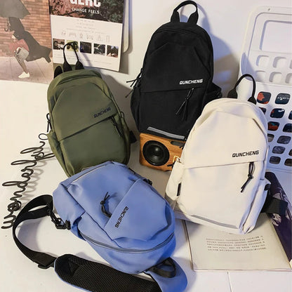 Four backpacks in green, black, blue, and white on a surface with visible text and graphics.