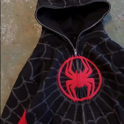 Black spider-web pattern hoodie with a red spider emblem on a textured surface