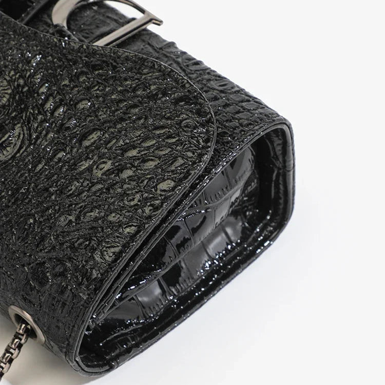 Black textured handbag with a chain detail on a white background
