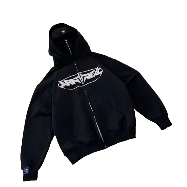 Person taking a photo of a black hoodie with a logo on a concrete floor.