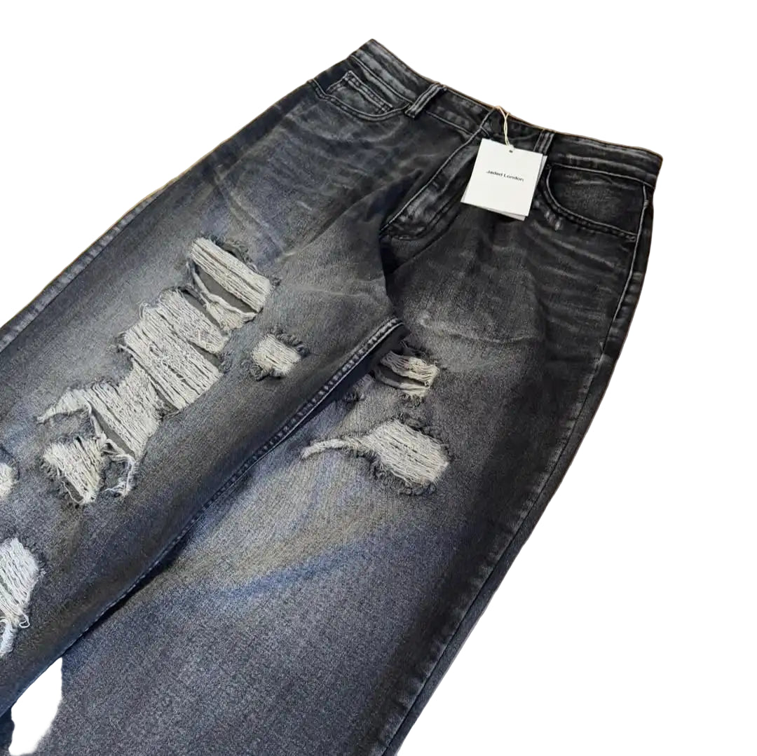 Ripped black jeans on a wooden floor with a tag attached.