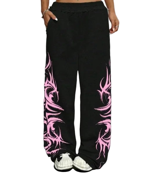 Person wearing black pants with pink tribal patterns on a gray floor.