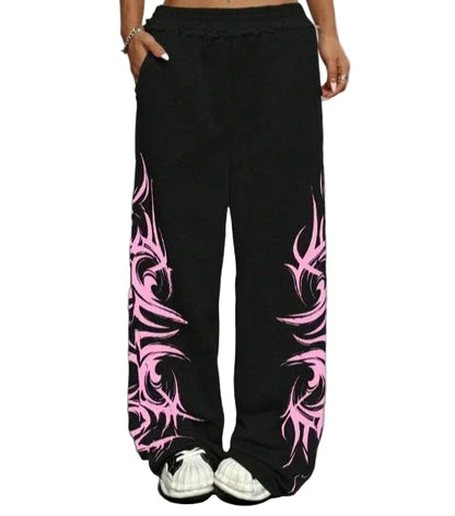 Person wearing black pants with pink tribal patterns on a gray floor.
