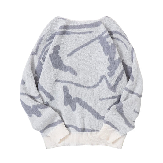 Gray patterned sweater on a gray surface with white sneakers and a book.