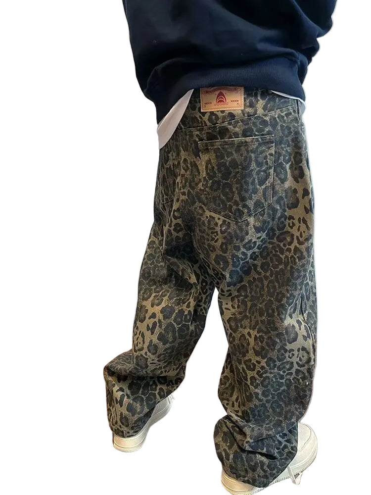 Person wearing leopard print pants with a visible brand label against a plain wall.
