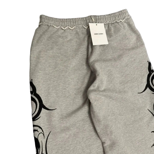 Gray sweatpants with black tribal designs on a gray surface