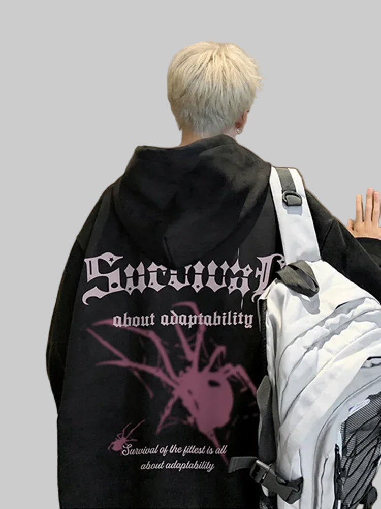 Person wearing a black hoodie with a graphic design and text, standing indoors.