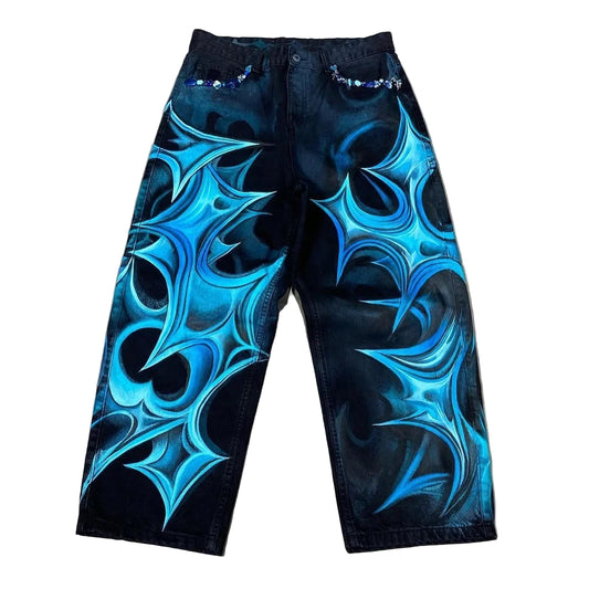 Black jeans with blue abstract patterns on a concrete floor